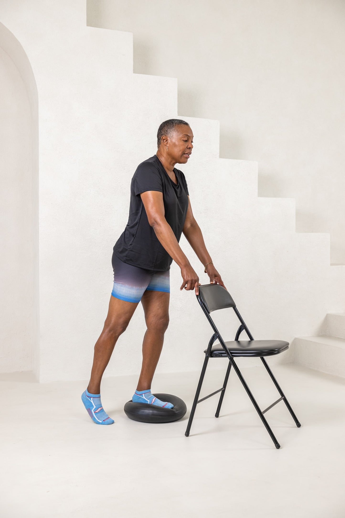 A women standing with a stability cushion to help build balance 60+